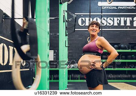 Stock Photo - Pregnant woman standing in gym. Fotosearch