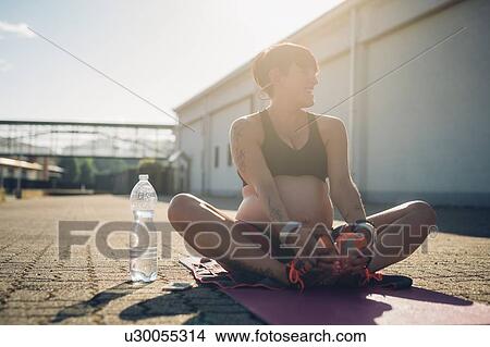Picture - Pregnant woman taking break from workout. Fotosearch
