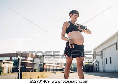 Stock Photo - Pregnant woman taking break from workout. Fotosearch