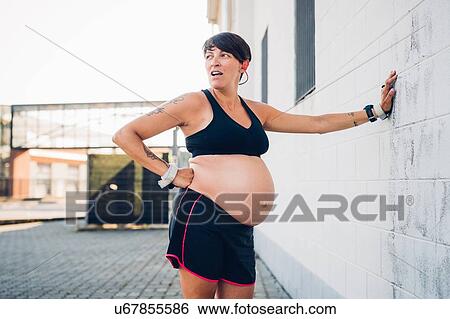Stock Photograph - Pregnant woman taking break from workout. Fotosearch