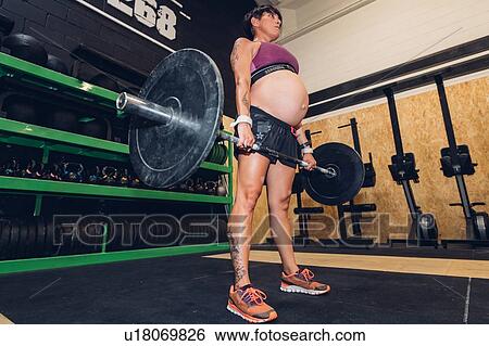 Pregnant woman using bar bell in gym View Large Photo Image Stock Photograph - Pregnant woman using bar bell in gym. Fotosearch