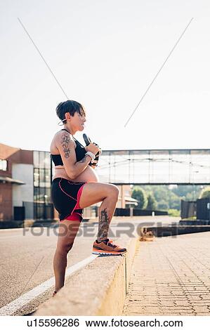 Stock Photograph - Pregnant woman using kettlebell outdoors. Fotosearch