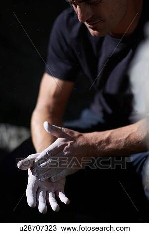 Stock Image - Rock climber dusting off climbing powder. Fotosearch