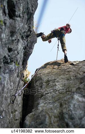 Stock Image - Rock climber jumping over rocks, Chamonix, Rhone-Alps, France. Fotosearch