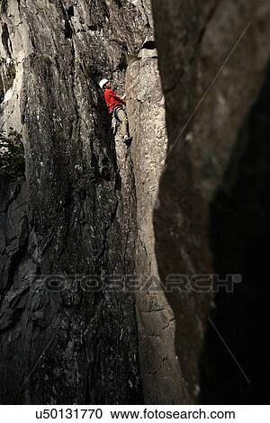 Stock Image - Rock climber scaling cliff face. Fotosearch