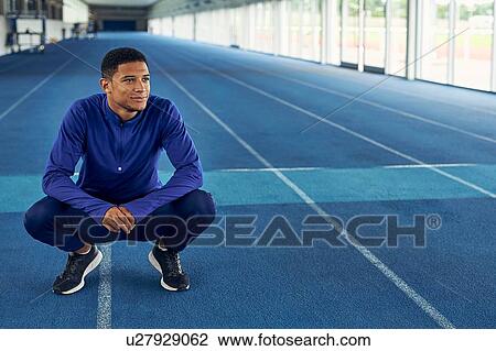 Stock Image - Runner resting on indoor running track. Fotosearch