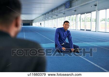 Stock Photo - Runners sitting on indoor running track. Fotosearch