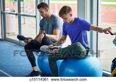Runners stretching on exercise balls in indoor running track View Large Photo Image Stock Image - Runners stretching on exercise balls in indoor running track. Fotosearch