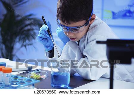 Stock Image - Schoolboy doing science experiment. Fotosearch