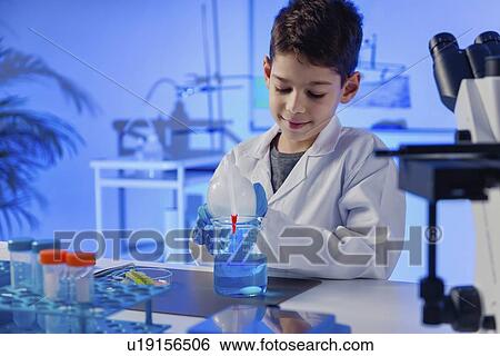 Stock Photograph - Schoolboy doing science experiment. Fotosearch
