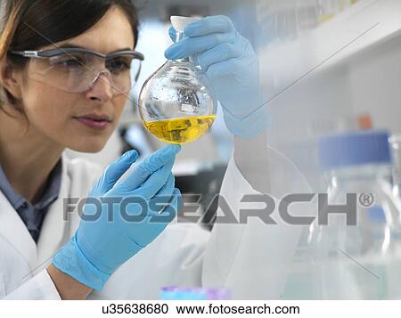 Stock Image - Scientist examining a solution in a laboratory flask during an experiment.. Fotosearch