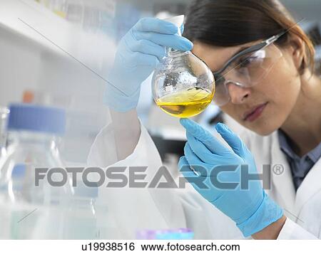 Scientist examining a solution in a laboratory flask during an experiment. View Large Photo Image Stock Photograph - Scientist examining a solution in a laboratory flask during an experiment.. Fotosearch