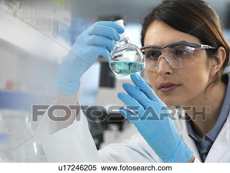 Scientist examining a solution in a laboratory flask during an experiment. View Large Photo Image Stock Photography - Scientist examining a solution in a laboratory flask during an experiment.. Fotosearch