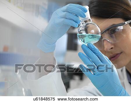 Scientist examining a solution in a laboratory flask during an experiment. View Large Photo Image Stock Photography - Scientist examining a solution in a laboratory flask during an experiment.. Fotosearch