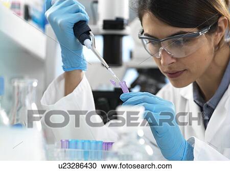Stock Image - Scientist pipetting sample into a tube for analytical testing in the laboratory.. Fotosearch
