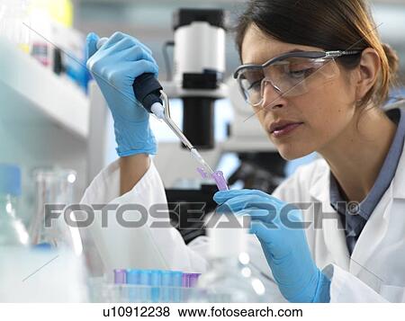 Stock Photo - Scientist pipetting sample into a tube for analytical testing in the laboratory.. Fotosearch
