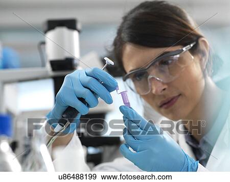 Stock Photo - Scientist pipetting sample into a tube for analytical testing in the laboratory.. Fotosearch