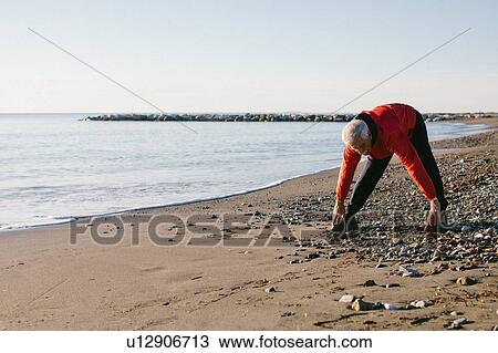 Senior man doing stretching exercises on beach, Livorno, Italy View Large Photo Image Stock Image - Senior man doing stretching exercises on beach, Livorno, Italy. Fotosearch