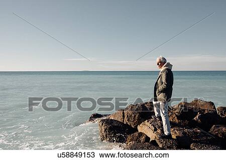 Stock Image - Senior man looking out to sea, Livorno, Italy. Fotosearch