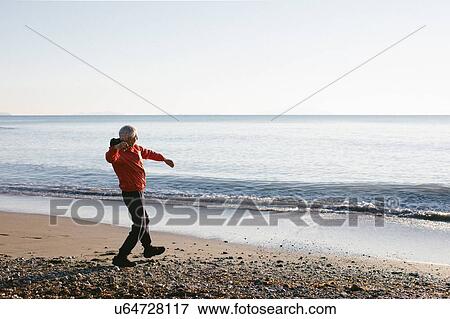 Senior man throwing pebbles into sea, Livorno, Italy View Large Photo Image Stock Photo - Senior man throwing pebbles into sea, Livorno, Italy. Fotosearch