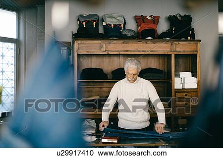 Stock Image - Senior man working in clothes shop. Fotosearch