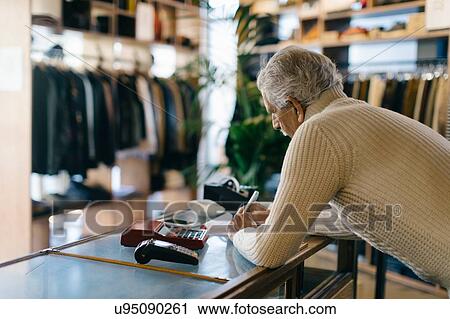 Stock Image - Senior man working in clothes shop. Fotosearch