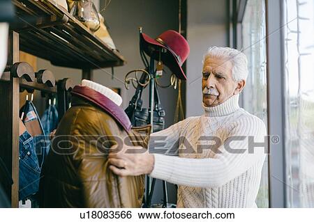 Stock Photograph - Senior man working in clothes shop. Fotosearch