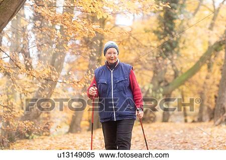 Stock Photography - Senior woman nordic walking in park. Fotosearch