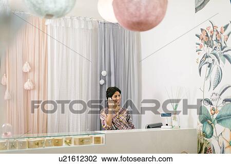 Shop keeper on telephone at cash till View Large Photo Image Stock Image - Shop keeper on telephone at cash till. Fotosearch