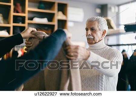 Shopper looking at garment in clothes shop View Large Photo Image Stock Photo - Shopper looking at garment in clothes shop. Fotosearch