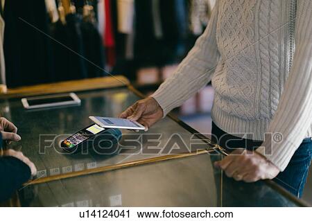 Shopper using mobile payment in clothes shop View Large Photo Image Stock Image - Shopper using mobile payment in clothes shop. Fotosearch