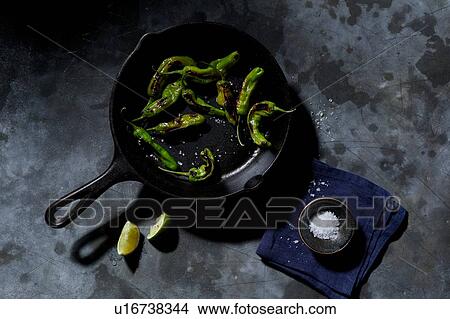 Skillet with saute shishito peppers with lime and sea salt, overhead view View Large Photo Image Picture - Skillet with saute shishito peppers with lime and sea salt, overhead view. Fotosearch