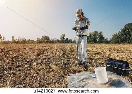 Stock Photo - Soil Sampling. Female agronomist taking sample with soil probe sampler.. Fotosearch