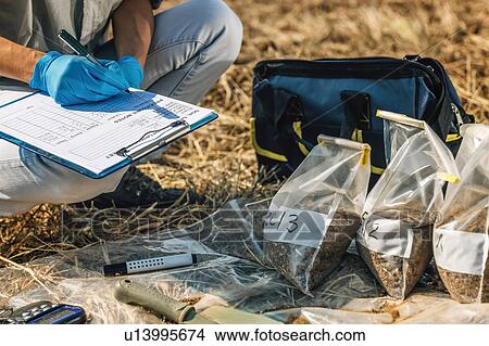 Picture - Soil Test. Female agronomist taking notes in the field.. Fotosearch