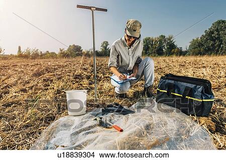 Picture - Soil Test. Female agronomist taking notes in the field.. Fotosearch