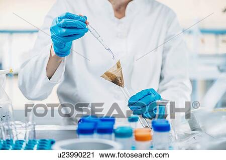 Stock Image - Soil testing. Close up hands of the scientist in laboratory mixing samples of the soil with reagent.. Fotosearch