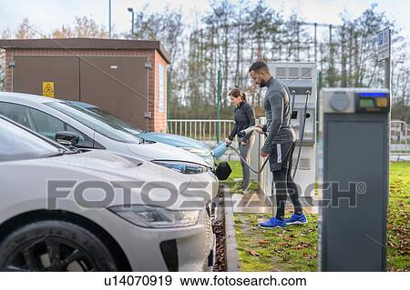 Sportsman and woman charging electric car at charging bay, Manchester, UK View Large Photo Image Stock Photo - Sportsman and woman charging electric car at charging bay, Manchester, UK. Fotosearch