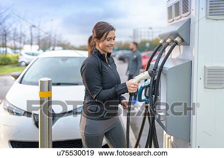 Sportswoman at electric car charging point, Manchester, UK View Large Photo Image Stock Photo - Sportswoman at electric car charging point, Manchester, UK. Fotosearch