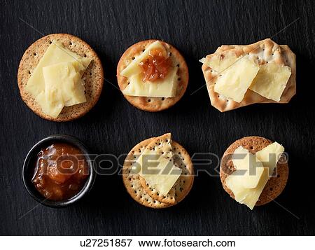 Still life of variety of cheese crackers with cheddar cheese and chutney on black slate, overhead view View Large Photo Image Stock Photo - Still life of variety of cheese crackers with cheddar cheese and chutney on black slate, overhead view. Fotosearch