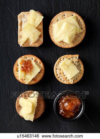 Still life of variety of cheese crackers with cheddar cheese and chutney on black slate, overhead view View Large Photo Image Stock Photograph - Still life of variety of cheese crackers with cheddar cheese and chutney on black slate, overhead view. Fotosearch