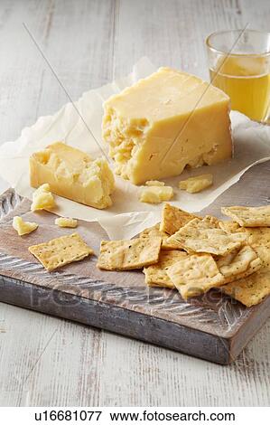 Stock Photo - Still life with cheddar cheese and crackers on cutting board. Fotosearch