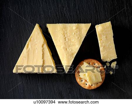 Picture - Still life with cheese cracker and cheddar cheese triangles on black slate, overhead view. Fotosearch