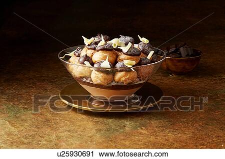 Stock Image - Still life with chocolate profiteroles on gold plate, christmas dessert. Fotosearch