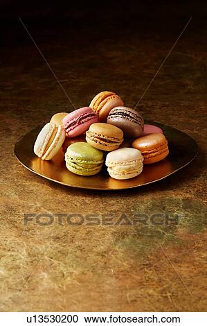 Stock Image - Still life with flavoured macaroons on gold plate. Fotosearch