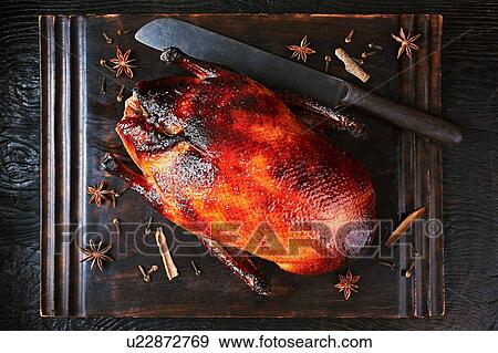 Stock Photo - Still life with peking duck on cutting board, overhead view. Fotosearch