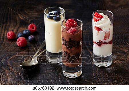 Stock Image - Still life with three desserts in glasses with raspberry and blackberry garnish. Fotosearch