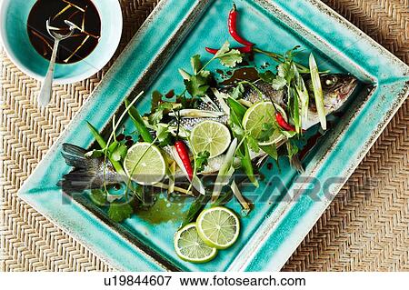Still life with whole roasted bass on serving dish, overhead view View Large Photo Image Stock Photo - Still life with whole roasted bass on serving dish, overhead view. Fotosearch