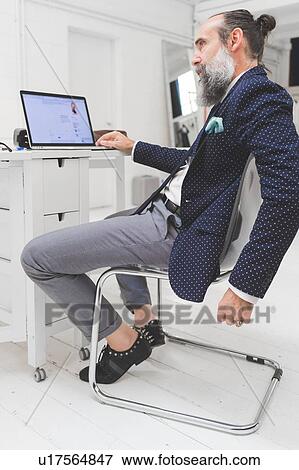 Stock Photo - Stylish businessman looking at laptop on office desk. Fotosearch
