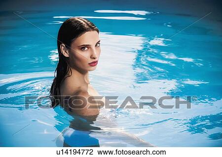 Stock Image - Sultry young woman standing in outdoor swimming pool, portrait, Cagliari, Sardinia, Italy. Fotosearch