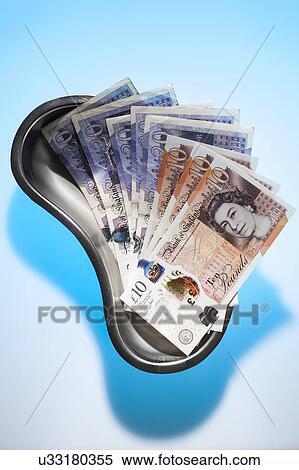 Stock Photography - Surgical dish and money depicting medical costs.. Fotosearch